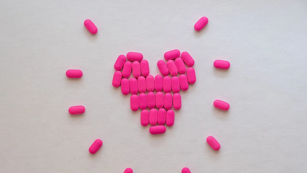 Pink pills arranged in a heart shape on a neutral surface. Perfect for health and medication themes.