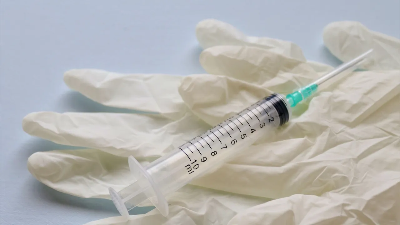 Close-up of a syringe and medical gloves on a flat surface, showcasing healthcare tools.