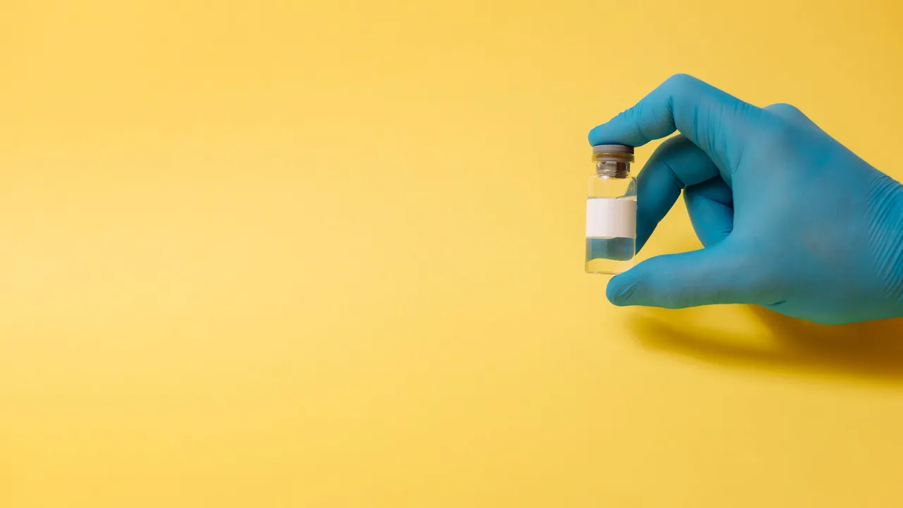 A gloved hand holds a medical vial against a bright yellow background, symbolizing health and medicine.