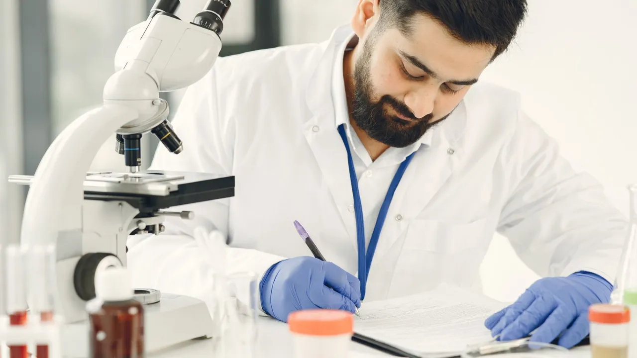 Male scientist in a laboratory, examining samples and taking notes.