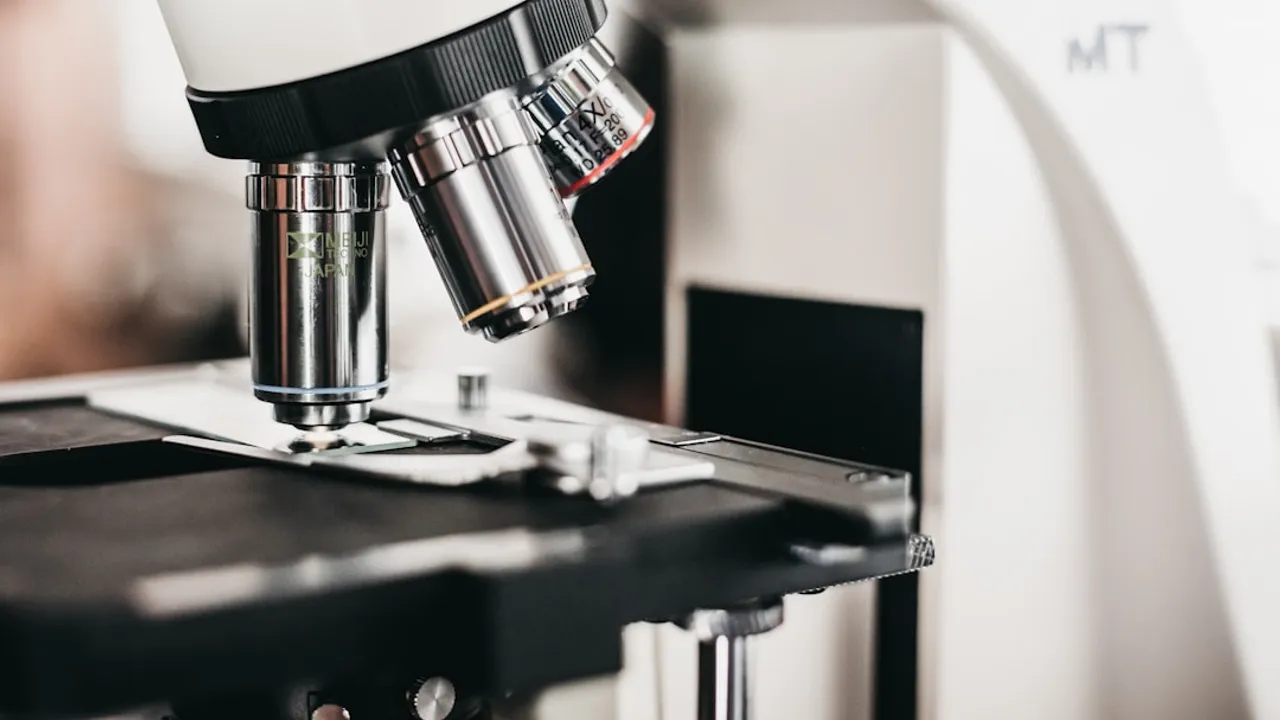 A Meiji Techno microscope with multiple objective lenses above a black stage