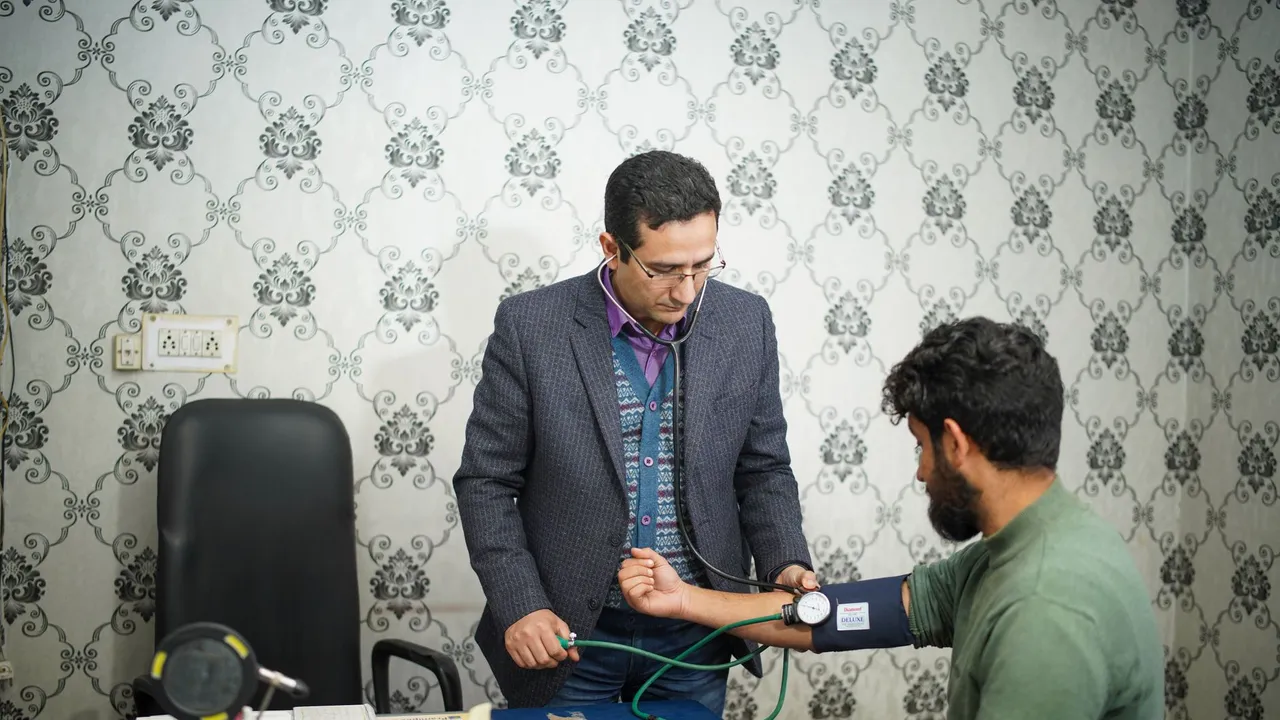 Doctor takes elderly patient's blood pressure.