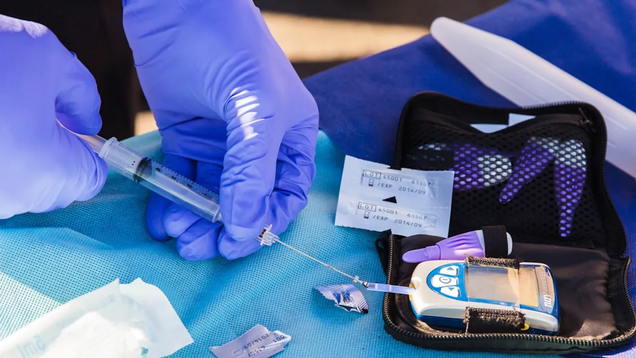person using disposable syringe put specimen on blue and white glucose meter